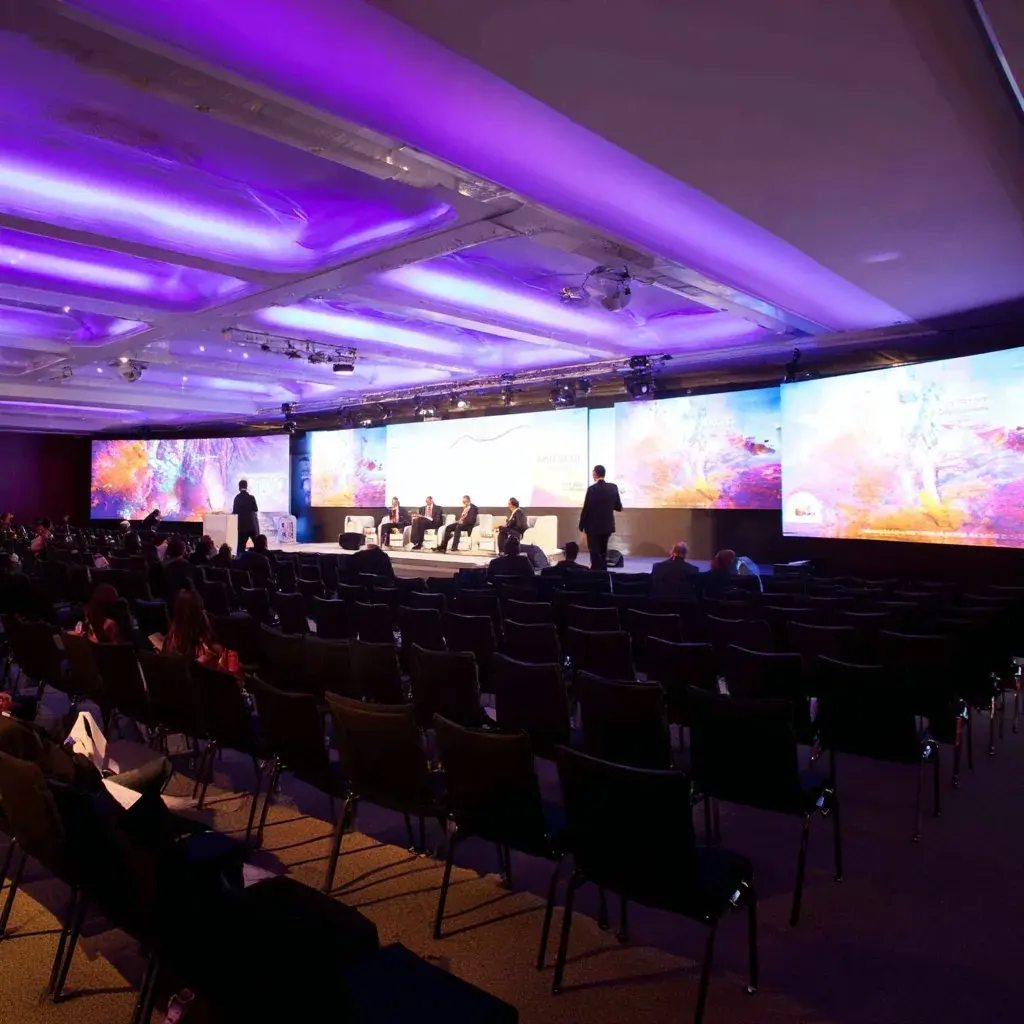 Corporate conference event with attendees, professional lighting, and event production setup