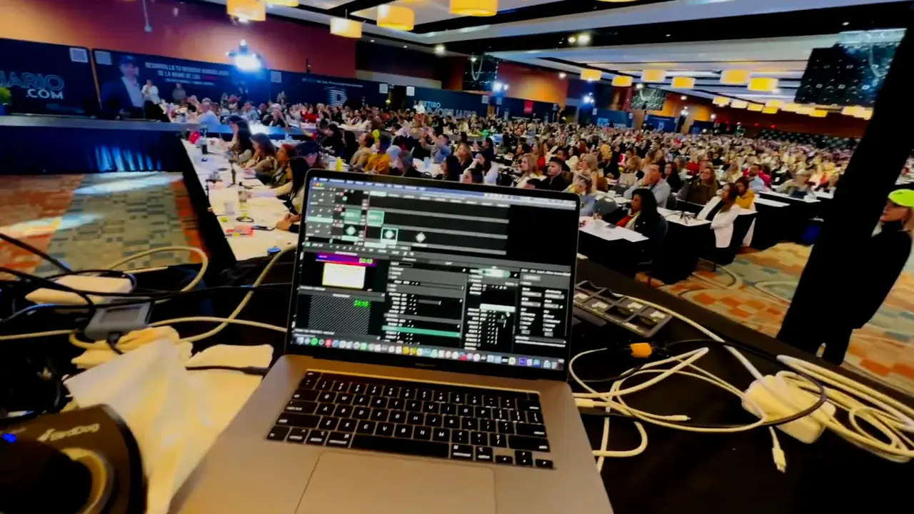 Production laptop overlooking a full conference audience