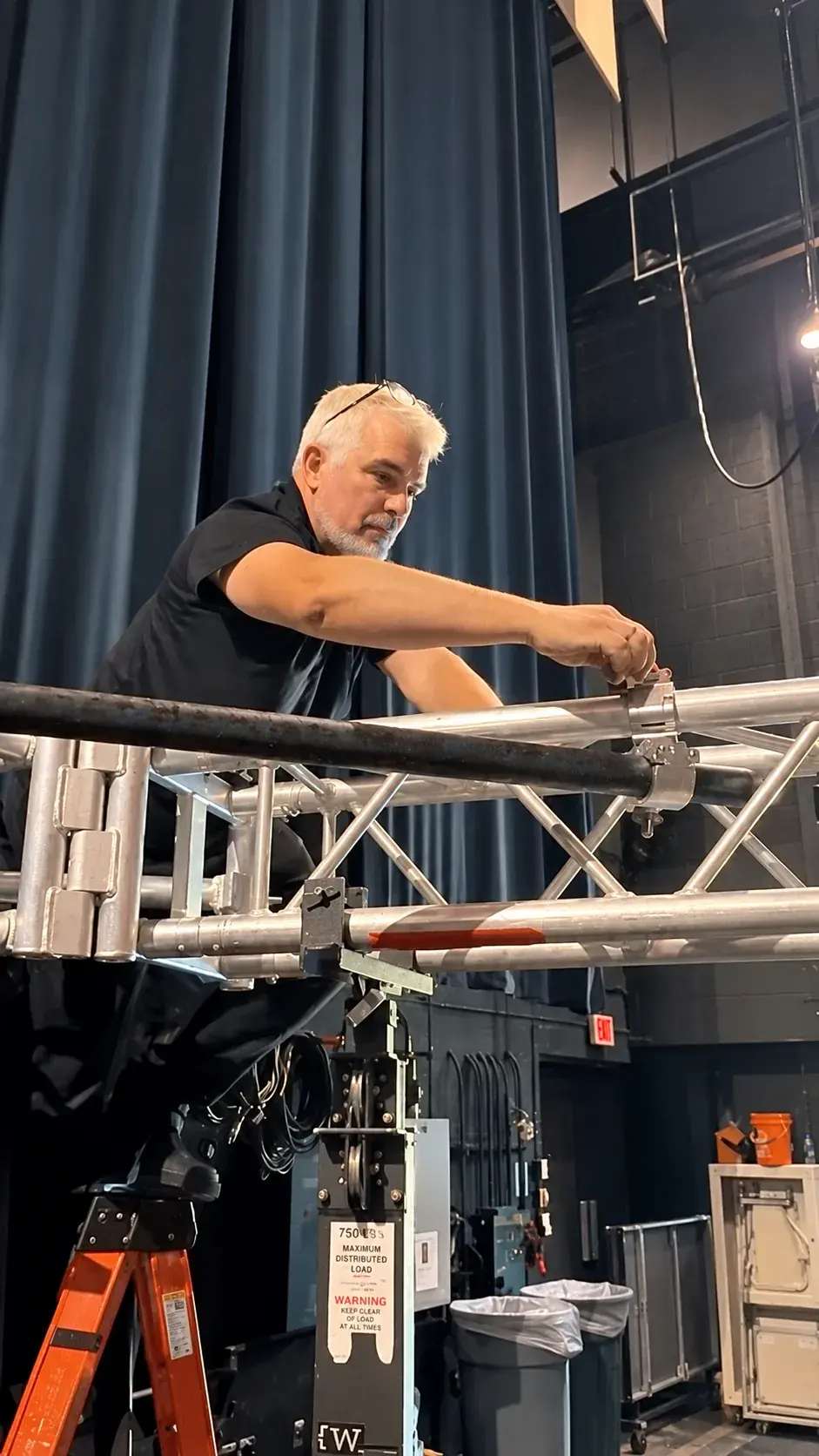 BE crew member fastening a truss connection on a theater stage