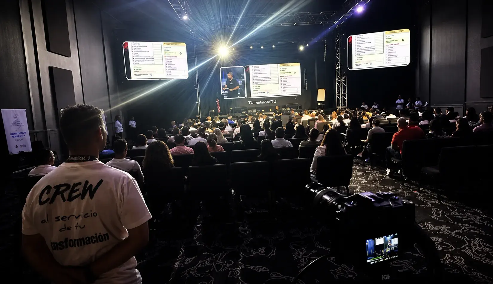 Event video production crew monitoring a conference from behind the audience
