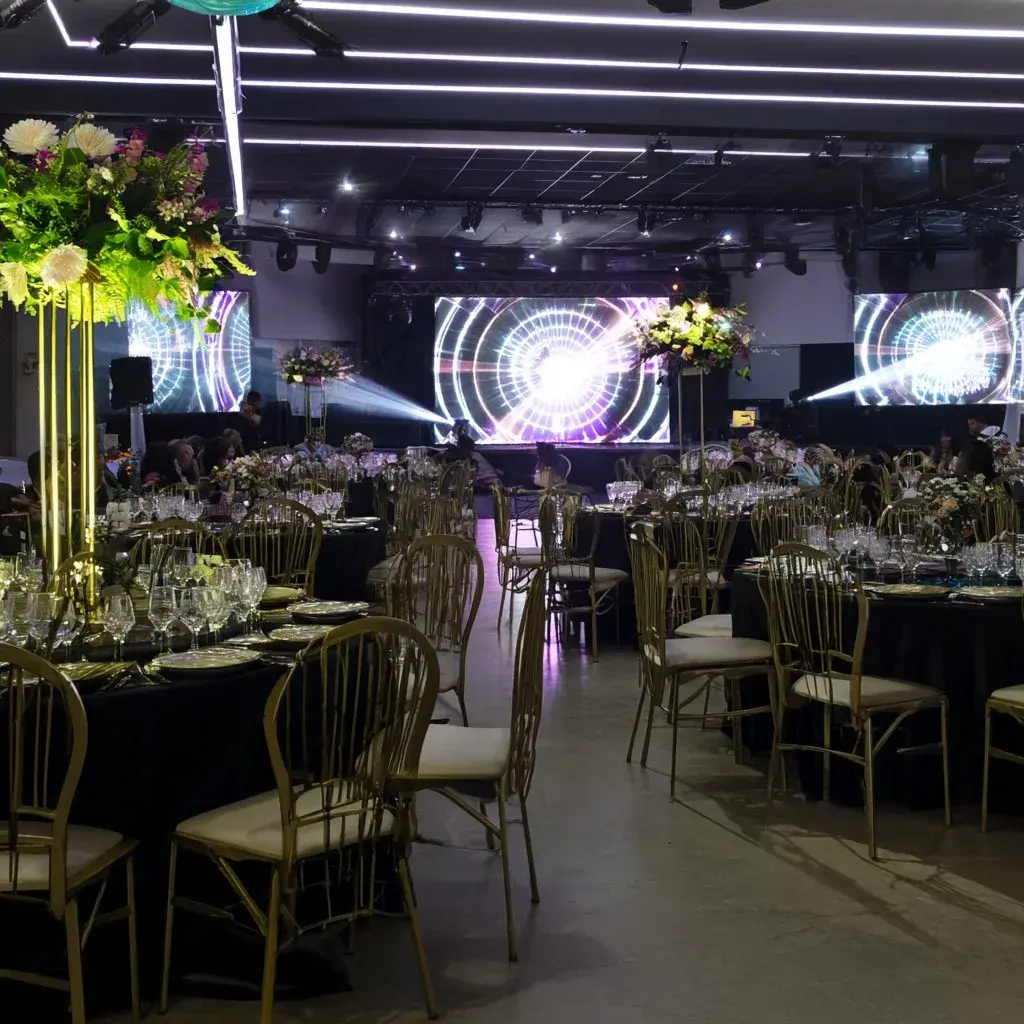 Elegant gala and awards room with chandeliers, banquet tables, stage lighting, and LED screens
